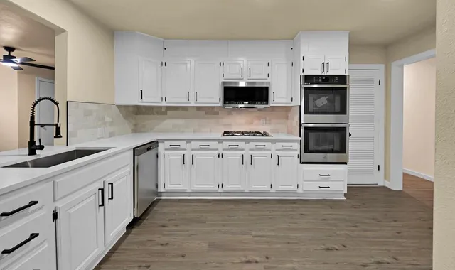 a kitchen with stainless steel appliances white cabinets a sink and a stove