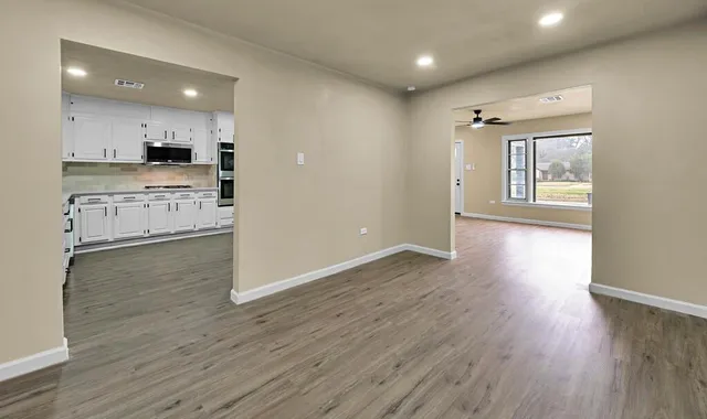 a view of a kitchen with kitchen island a sink wooden floor and stainless steel appliances