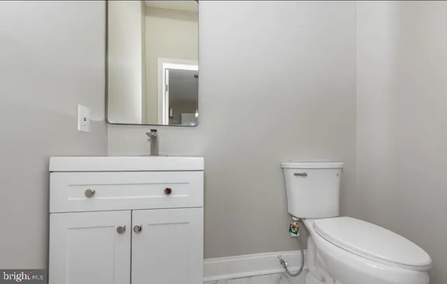a bathroom with a toilet sink vanity and mirror