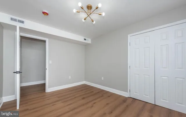 an empty room with wooden floor and ceiling fan