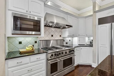 a kitchen with granite countertop a stove and white cabinets