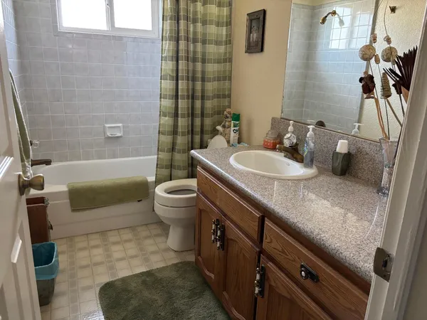 a bathroom with a granite countertop sink a toilet a mirror and shower