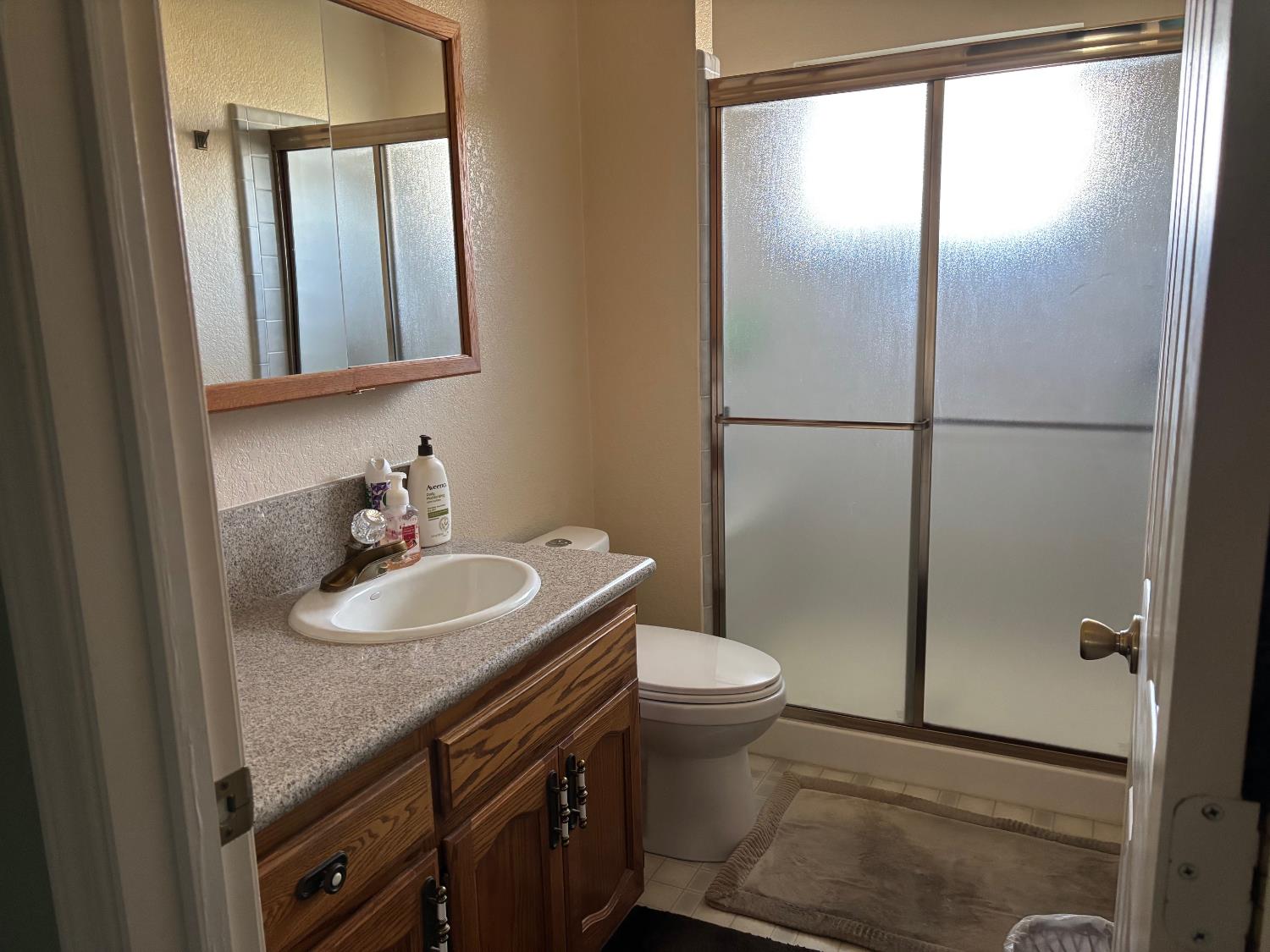 1691 Davis Street Ripon, CA 95366 - Photo 17 of 22 a bathroom with a sink a toilet and shower a mirror