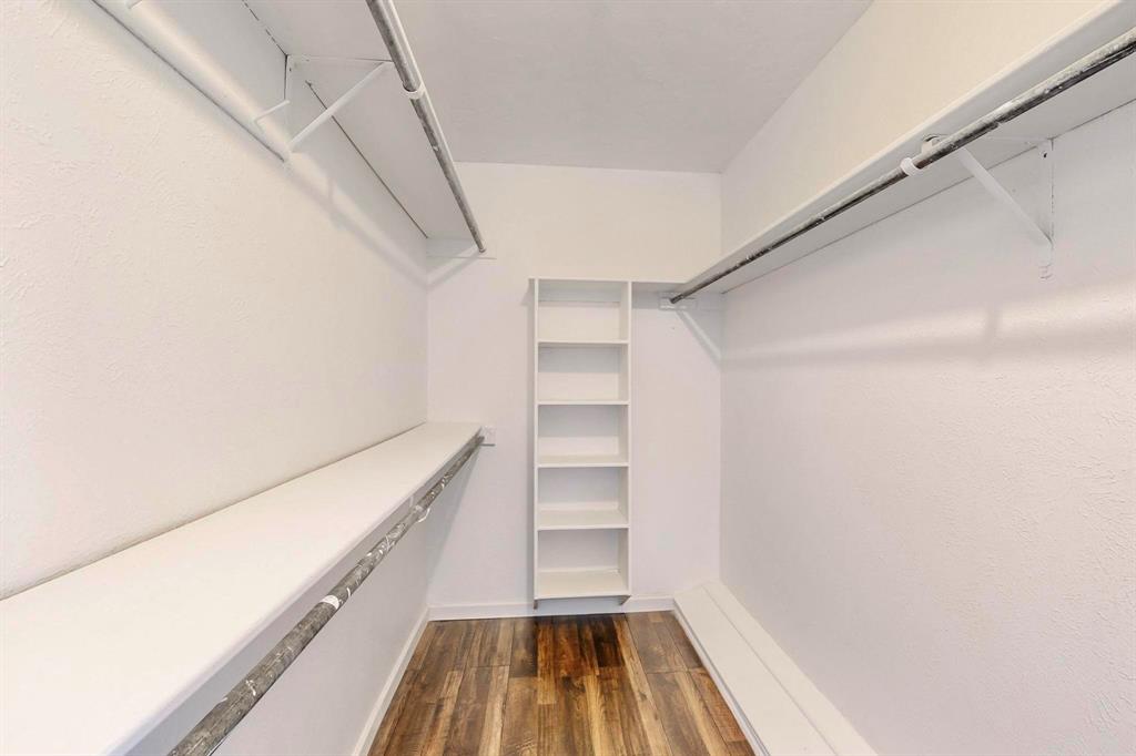 3965 Singleleaf Lane Fort Worth, TX 76133 - Photo 20 of 39 Walk-in closet featuring wood-finish flooring, white walls, built-in shelving, and dual clothing rods with overhead shelving