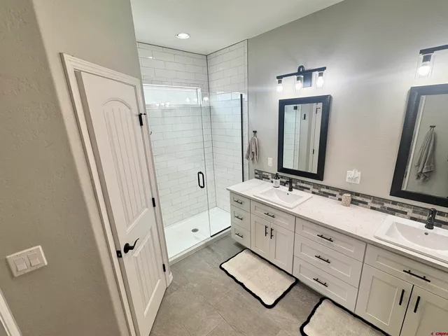 a bathroom with double vanity and a mirror