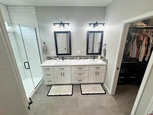 a bathroom with double vanity sink and two mirror