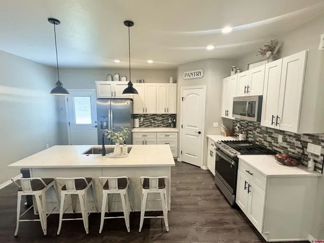 a kitchen with a dining table chairs stainless steel appliances and cabinets