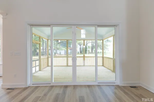 an empty room with wooden floor and glass door