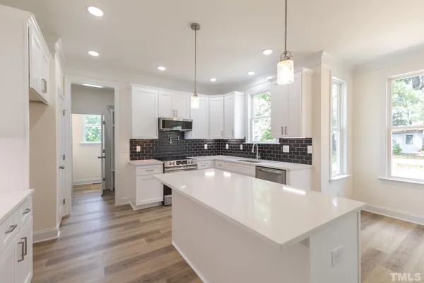 a large kitchen with kitchen island a large counter top a refrigerator and cabinets