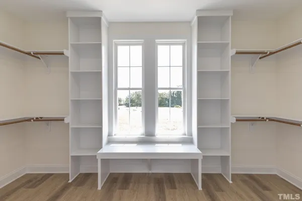 a view of walk in closet with window and wooden floor