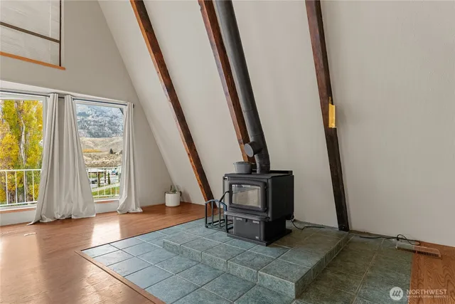 a view of an empty room with wooden floor and fan