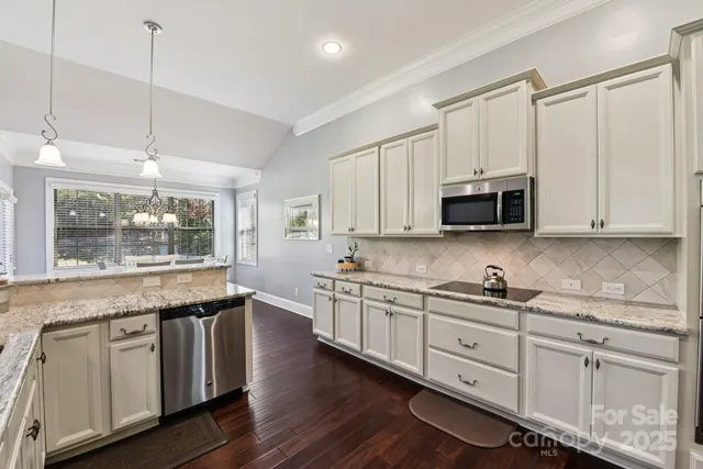 a kitchen with stainless steel appliances granite countertop white cabinets a sink and dishwasher with wooden floor