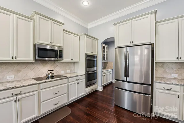 a kitchen with stainless steel appliances white cabinets white and wooden floors
