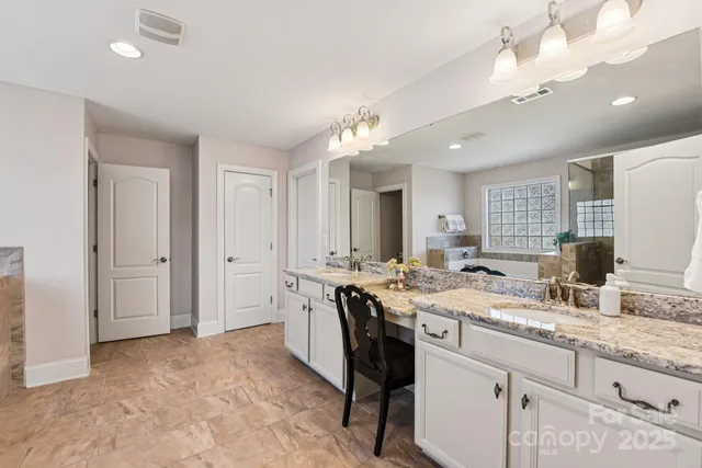 a spacious bathroom with a granite countertop sink a toilet a mirror and shower