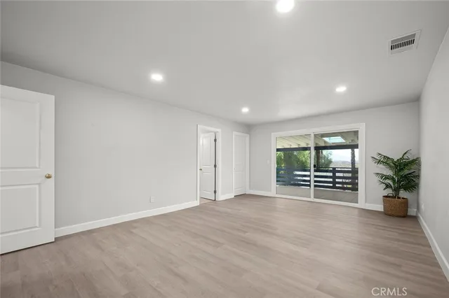 an empty room with wooden floor and natural light