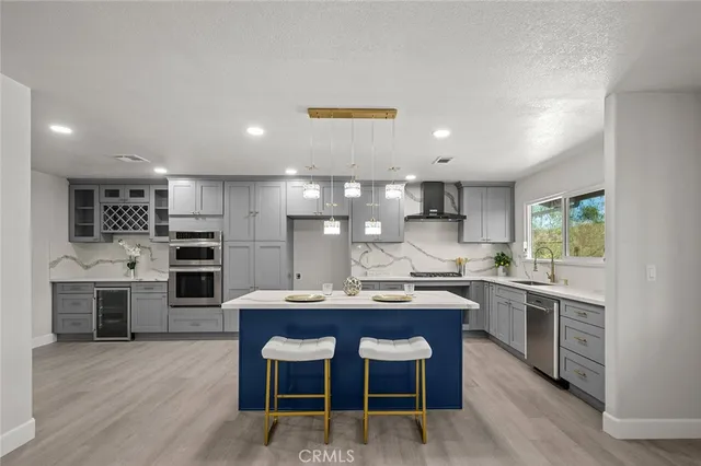 a kitchen with a refrigerator a sink dishwasher a stove and a dining table with wooden floor