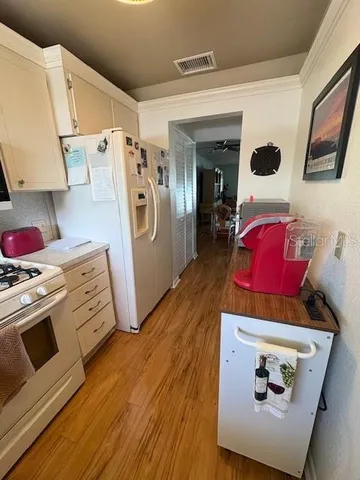 a view of a kitchen with fridge and wooden floor
