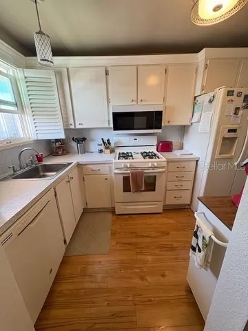 a view of kitchen with sink a microwave and cabinets