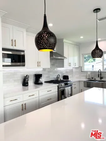 a kitchen with stainless steel appliances a sink a stove a microwave a center island and cabinets