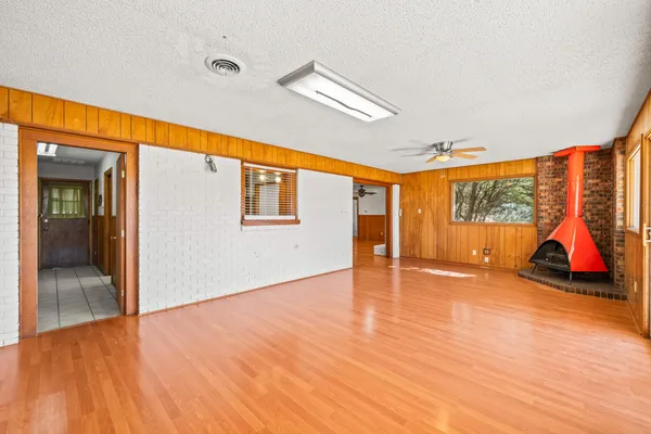 a view of an empty room with wooden floor and windows