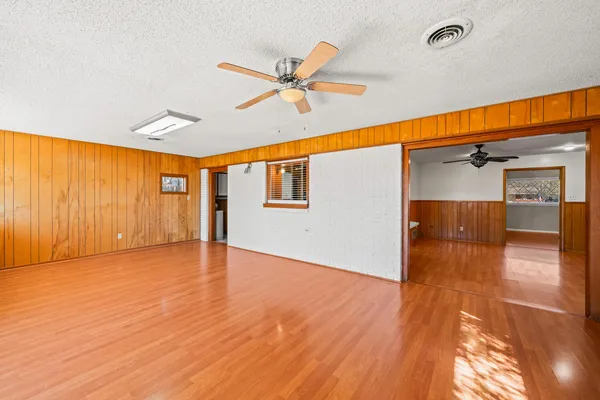 a view of empty room with wooden floor and fan