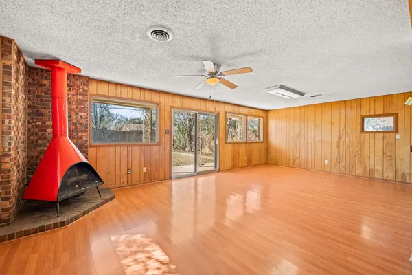 a view of an empty room with wooden floor and windows