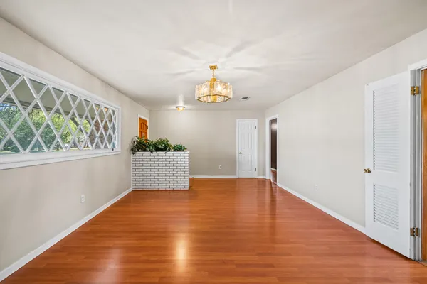 a view of an empty room with window and wooden floor