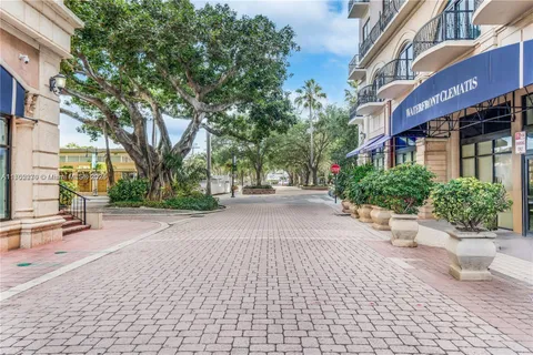 a view of a street with potted plants and large trees