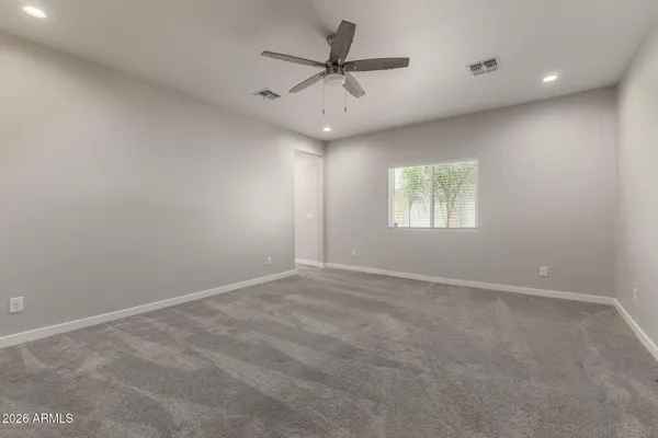 an empty room with a chandelier fan and windows
