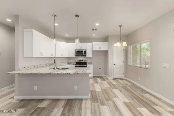 a large kitchen with granite countertop a large counter top a sink stainless steel appliances and cabinets