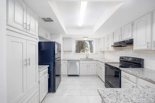 a kitchen with white cabinets sink and stainless steel appliances