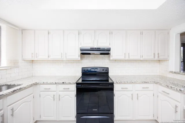 a kitchen with white cabinets and appliances
