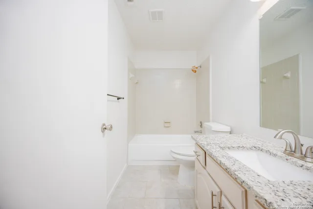 a bathroom with a granite countertop sink a toilet and shower