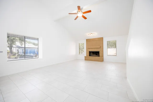an empty room with windows and fireplace