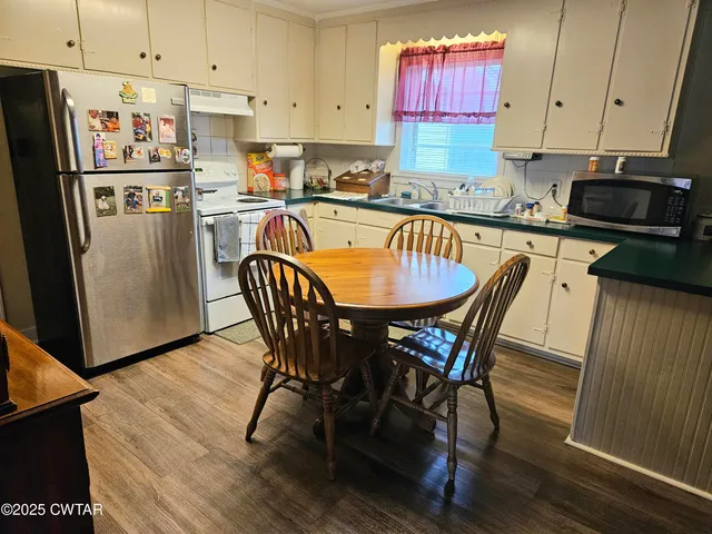 a kitchen with stainless steel appliances granite countertop a dining table chairs refrigerator and sink