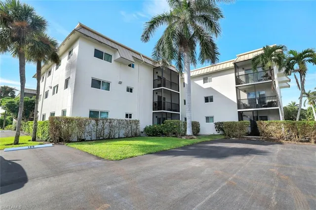 a view of a white house with a big yard and palm trees