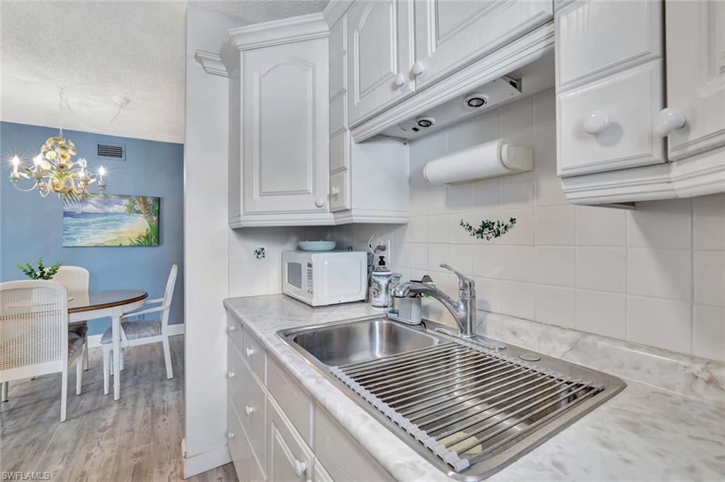 766 Central Avenue, Unit 303 Naples, FL 34102 - Photo 6 of 25 a kitchen with granite countertop a sink stove and cabinets