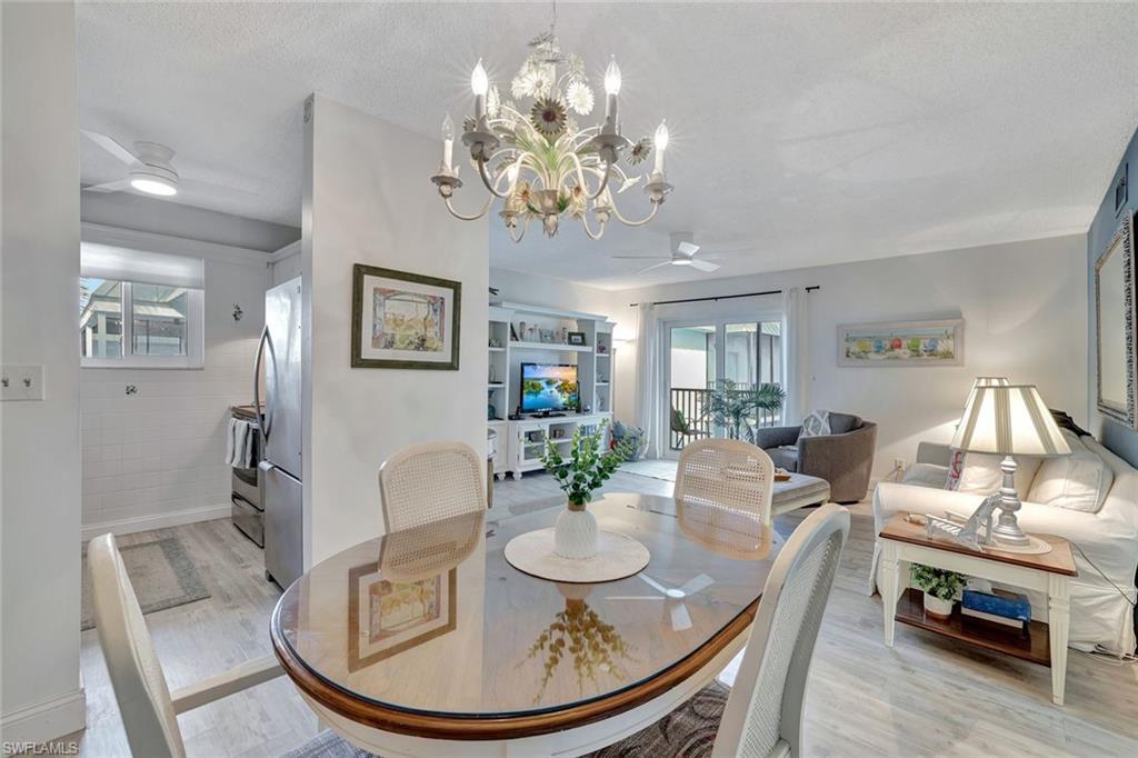 766 Central Avenue, Unit 303 Naples, FL 34102 - Photo 9 of 25 a view of a dining room with furniture a chandelier and wooden floor