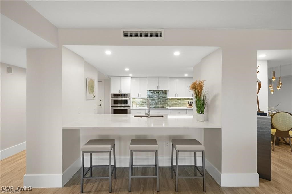 5601 Turtle Bay Drive, Unit 302 Naples, FL 34108 - Photo 12 of 44 a kitchen with kitchen island cabinets and chairs in it