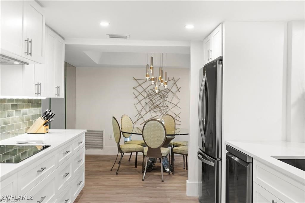 5601 Turtle Bay Drive, Unit 302 Naples, FL 34108 - Photo 10 of 44 a kitchen with stainless steel appliances granite countertop a table chairs in it and wooden floors