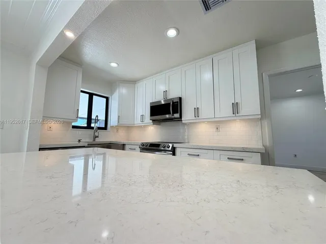 a kitchen with stainless steel appliances granite countertop a sink stove and microwave