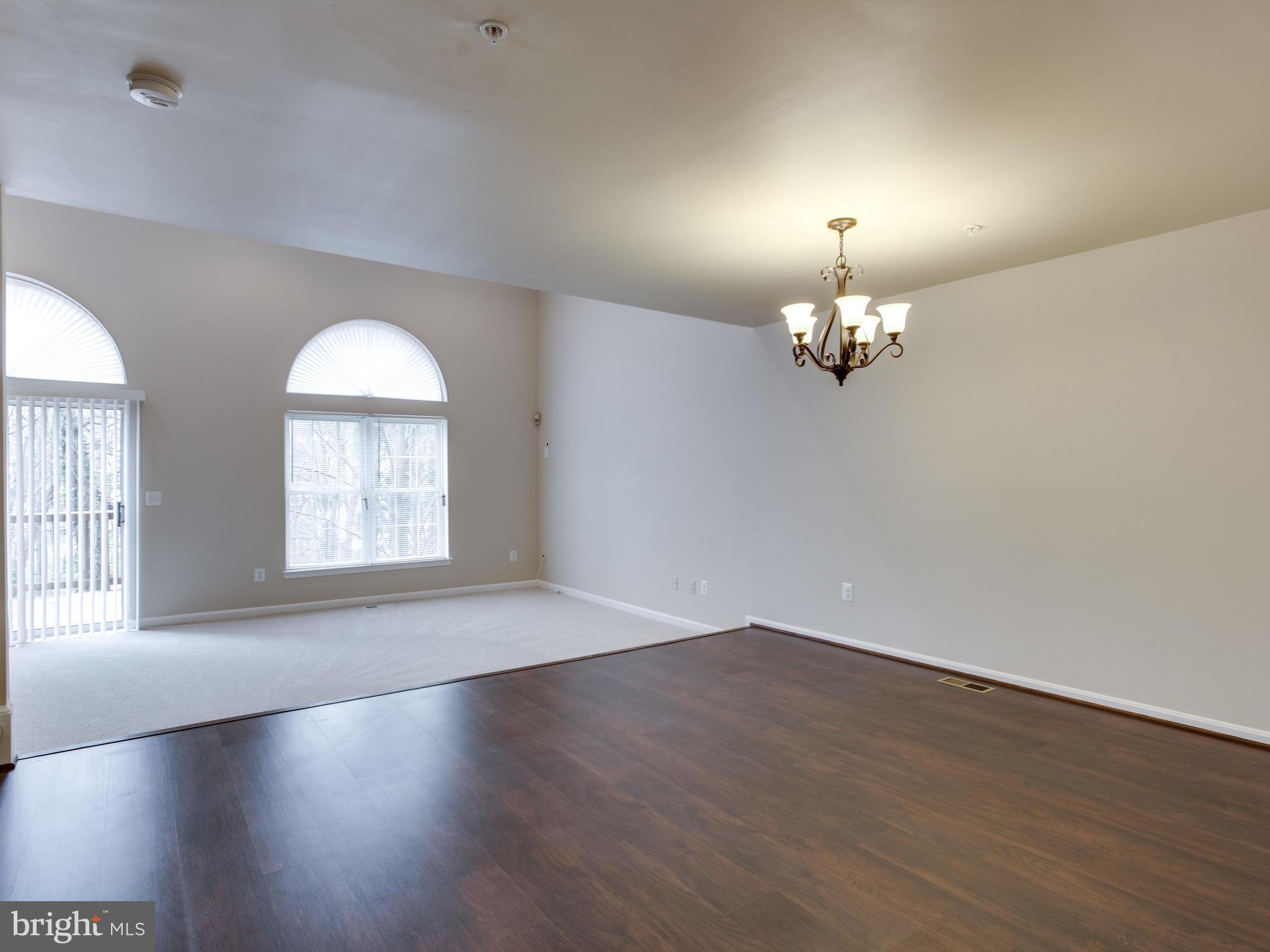 9320 Ispahan Loop Laurel, MD 20708 - Photo 11 of 30 an empty room with wooden floor chandelier and windows