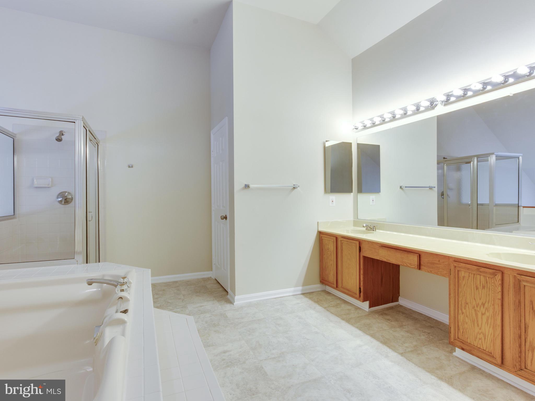 9320 Ispahan Loop Laurel, MD 20708 - Photo 25 of 30 a spacious bathroom with a double vanity sink a mirror and a bathtub