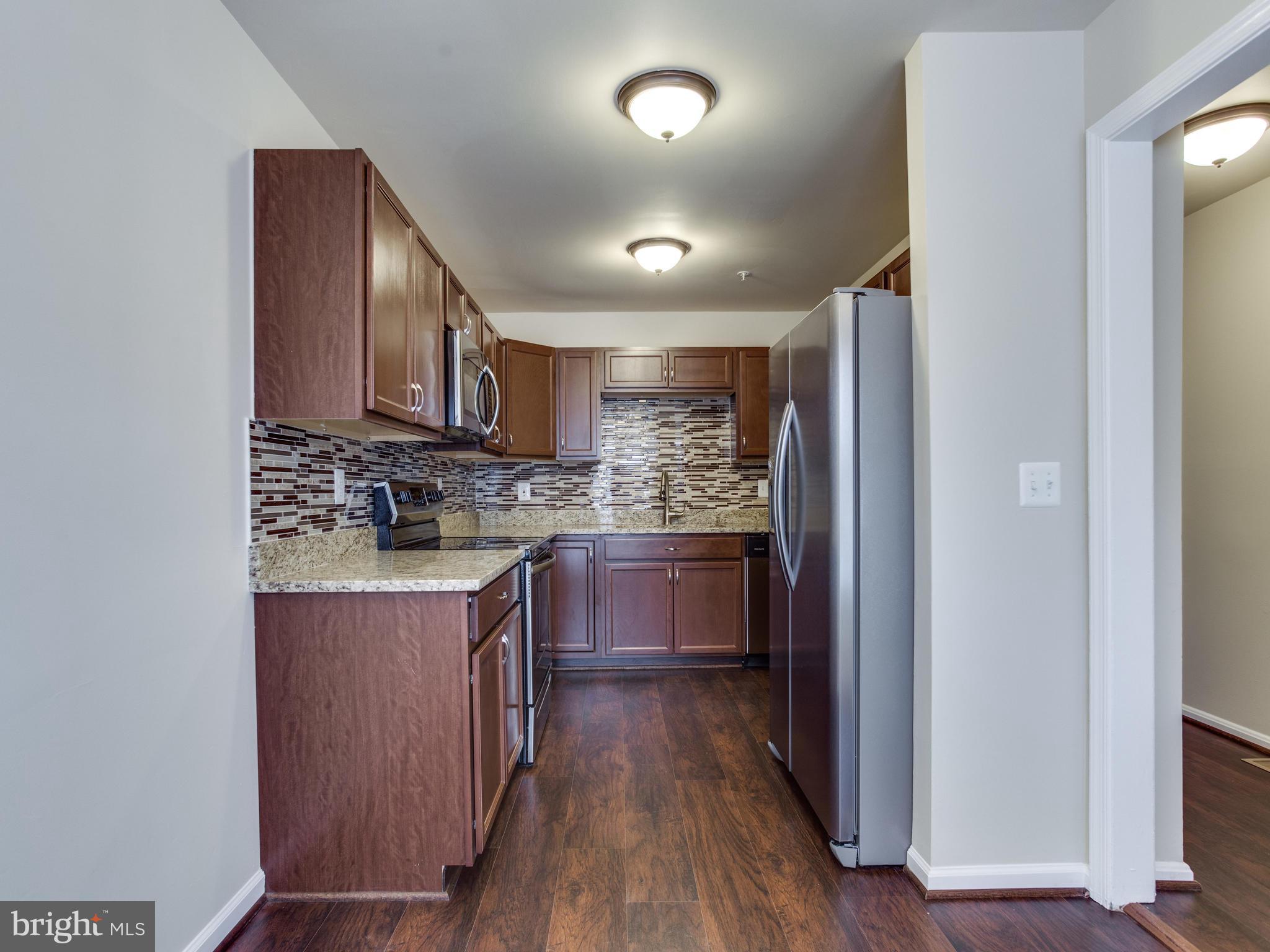 9320 Ispahan Loop Laurel, MD 20708 - Photo 5 of 30 a kitchen with stainless steel appliances granite countertop a stove a sink and a refrigerator with wooden floor