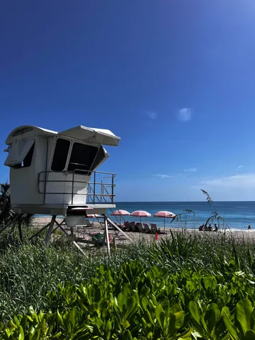 a view of a table and chairs under an umbrella in front of house