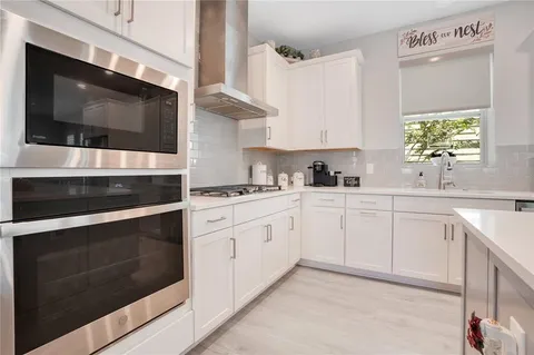 a kitchen with stainless steel appliances white cabinets and a stove top oven