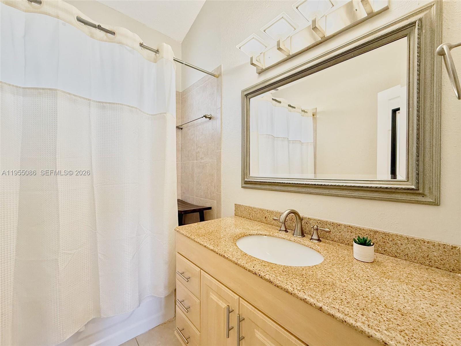 7034 Southwest 112th Court Miami, FL 33173 - Photo 33 of 39 a bathroom with a granite countertop sink and a mirror