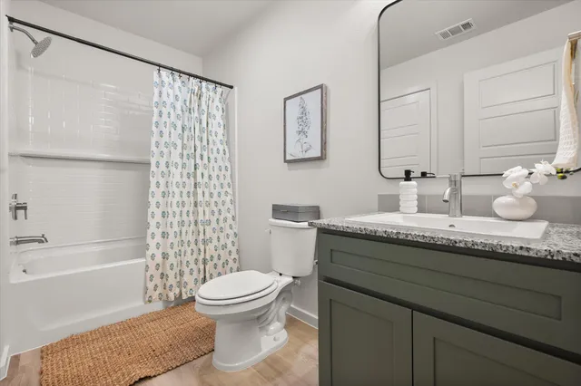 a bathroom with a granite countertop sink a toilet and shower