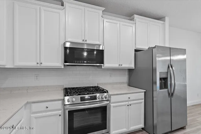 a kitchen with stainless steel appliances white cabinets white stove a refrigerator and a microwave