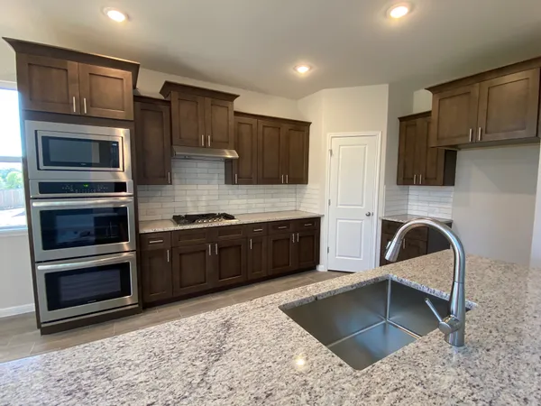 a kitchen with stainless steel appliances kitchen island granite countertop a stove sink and microwave